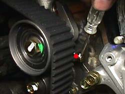 Screw driver is pointing to the retaining bolt on the auto-tensioner